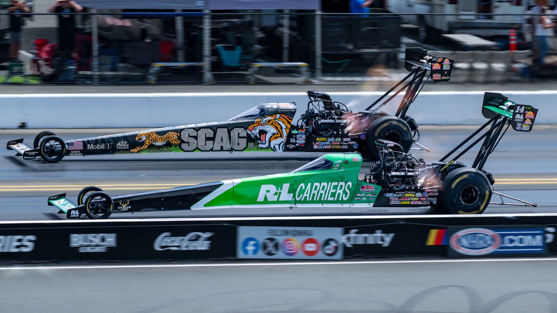 A tiger-liveried top fuel dragster racing a green and white dragster.