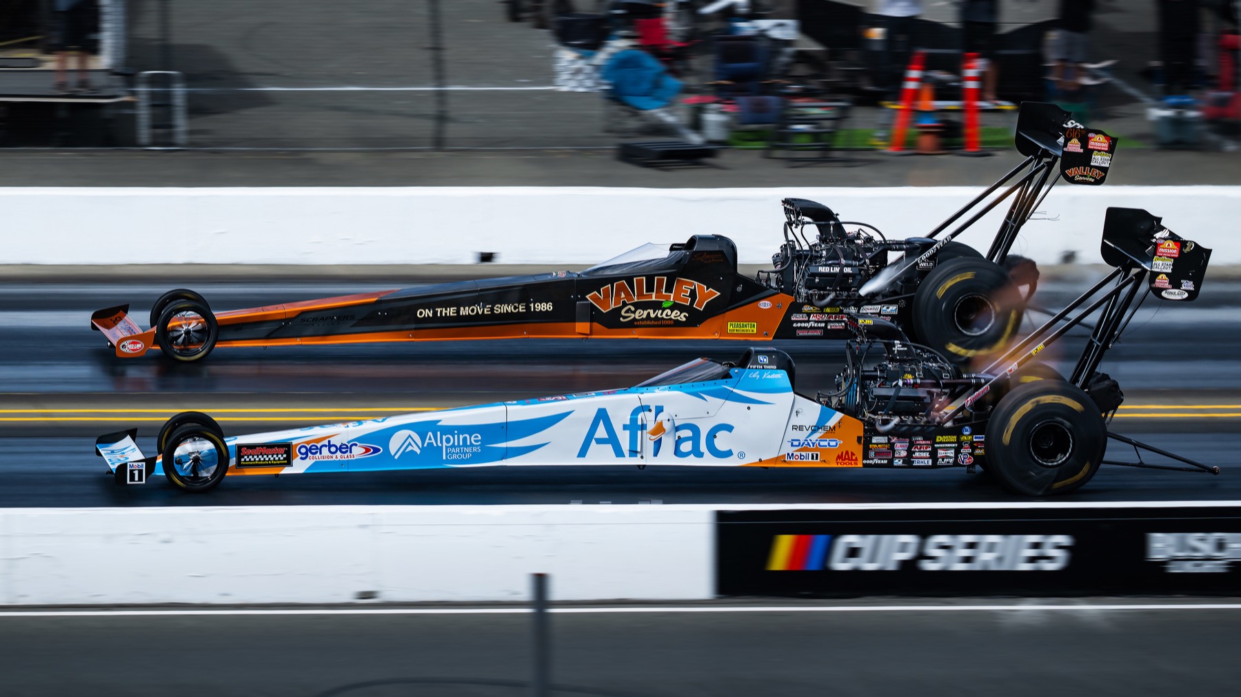 Two top fuel dragsters mid-launch, front wheels light off the asphalt.