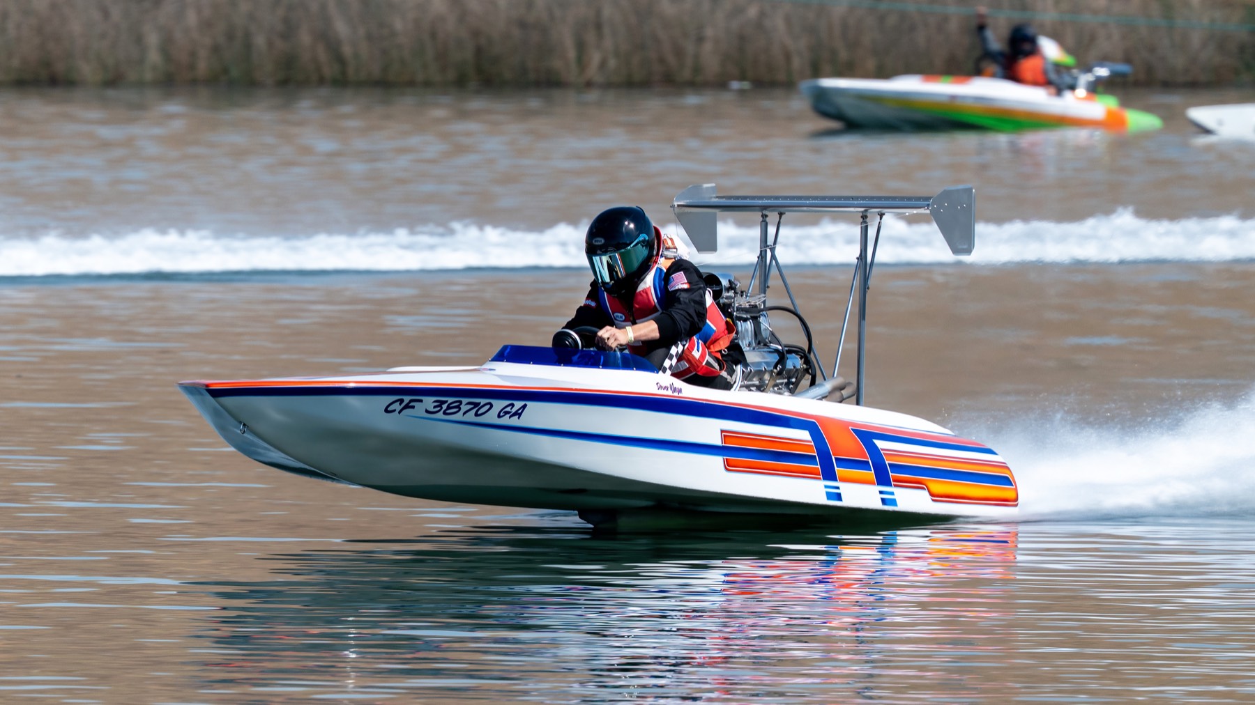 A drag boat charging toward the camera, bow up, another boat visible behind.